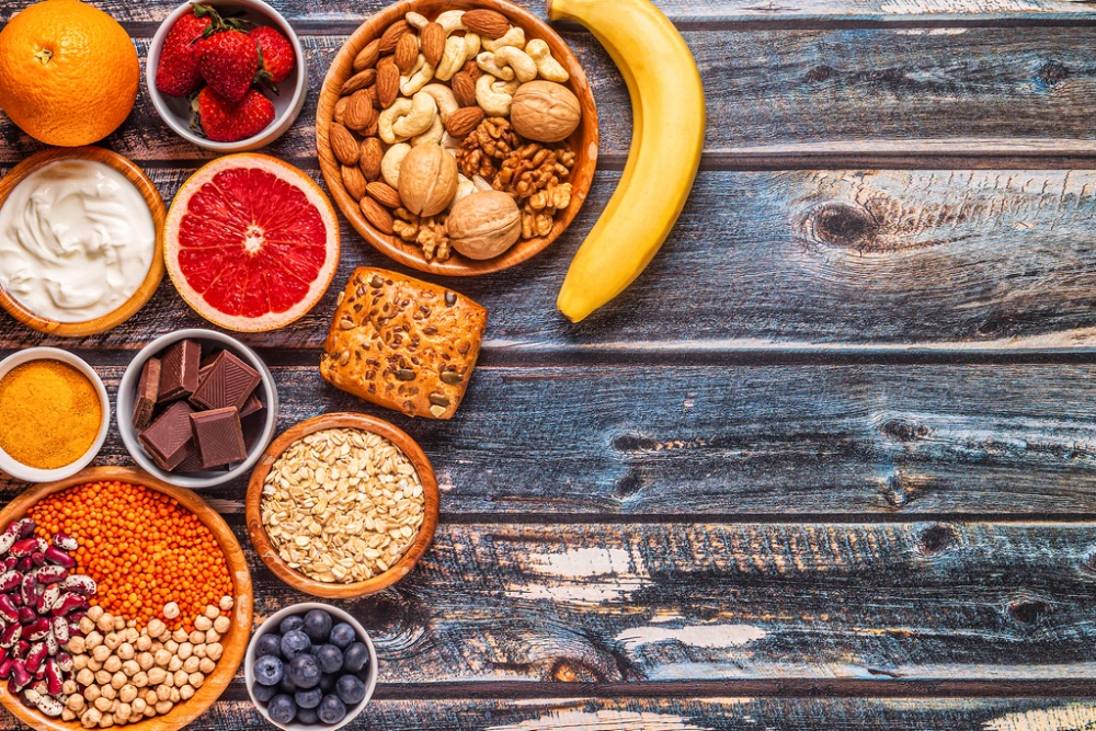 Flat lay of healthy foods including fruits, nuts, berries, and legumes