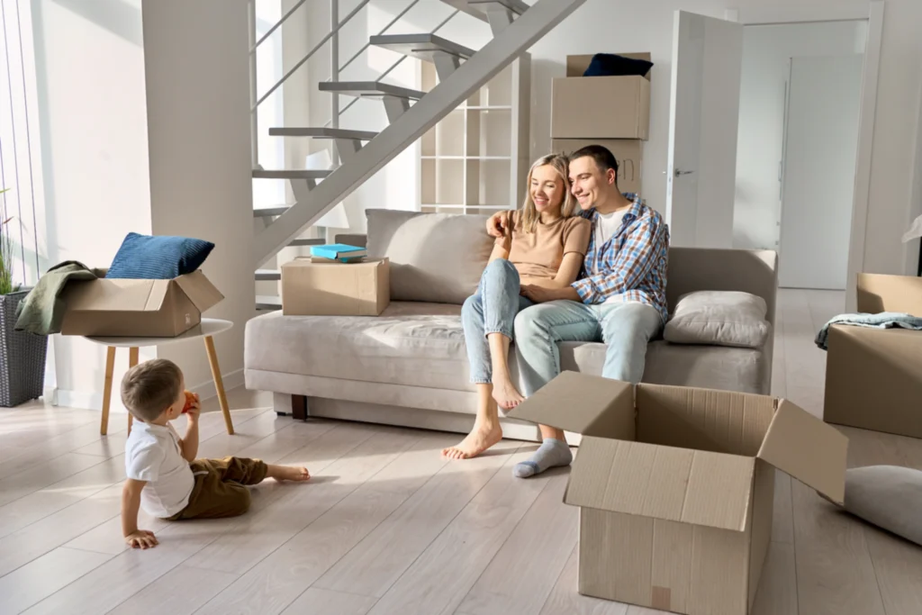 Happy family sitting on sofa surrounded by moving boxes in new home