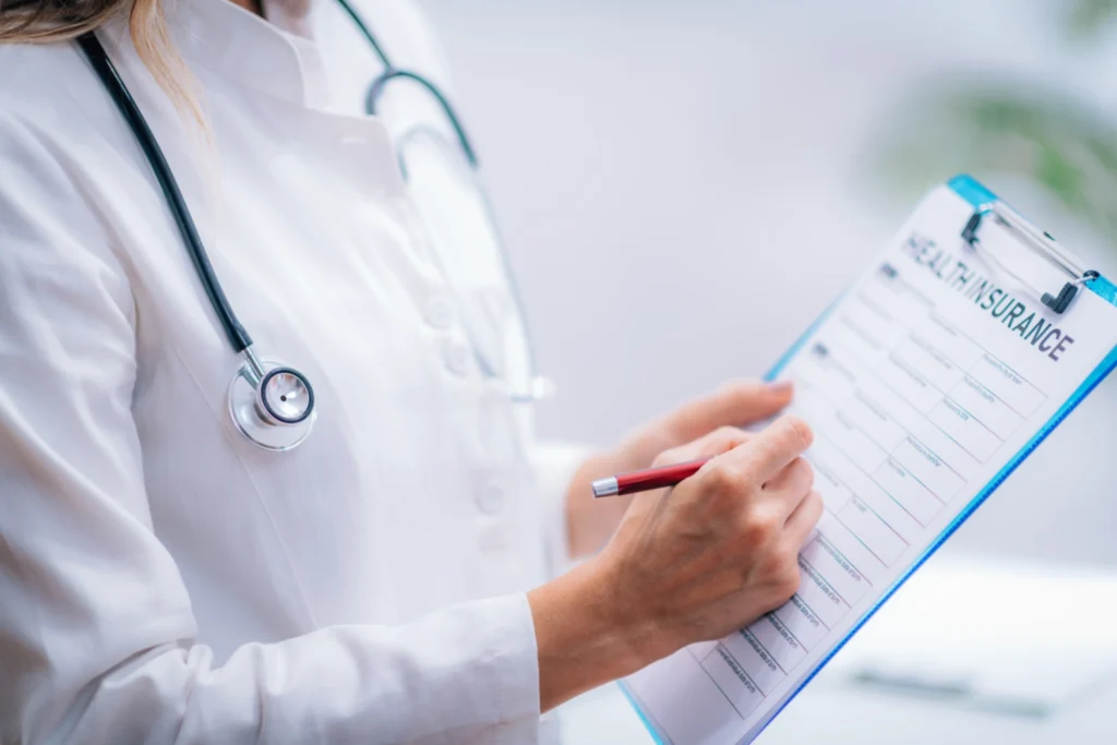 Female doctor in white coat writing on a health insurance form