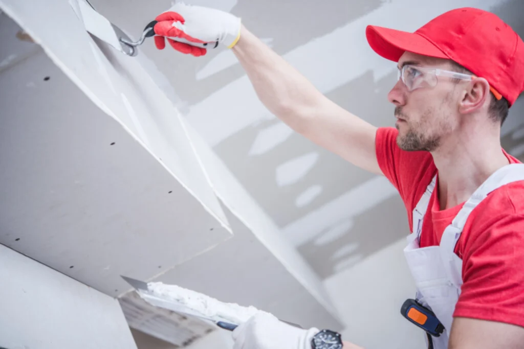 Construction worker applying plaster to a drywall ceiling
