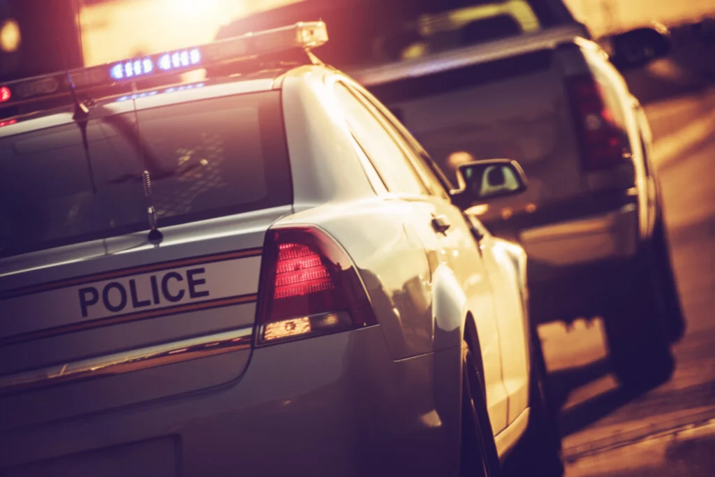 Police car with flashing lights pulling over a truck on a highway