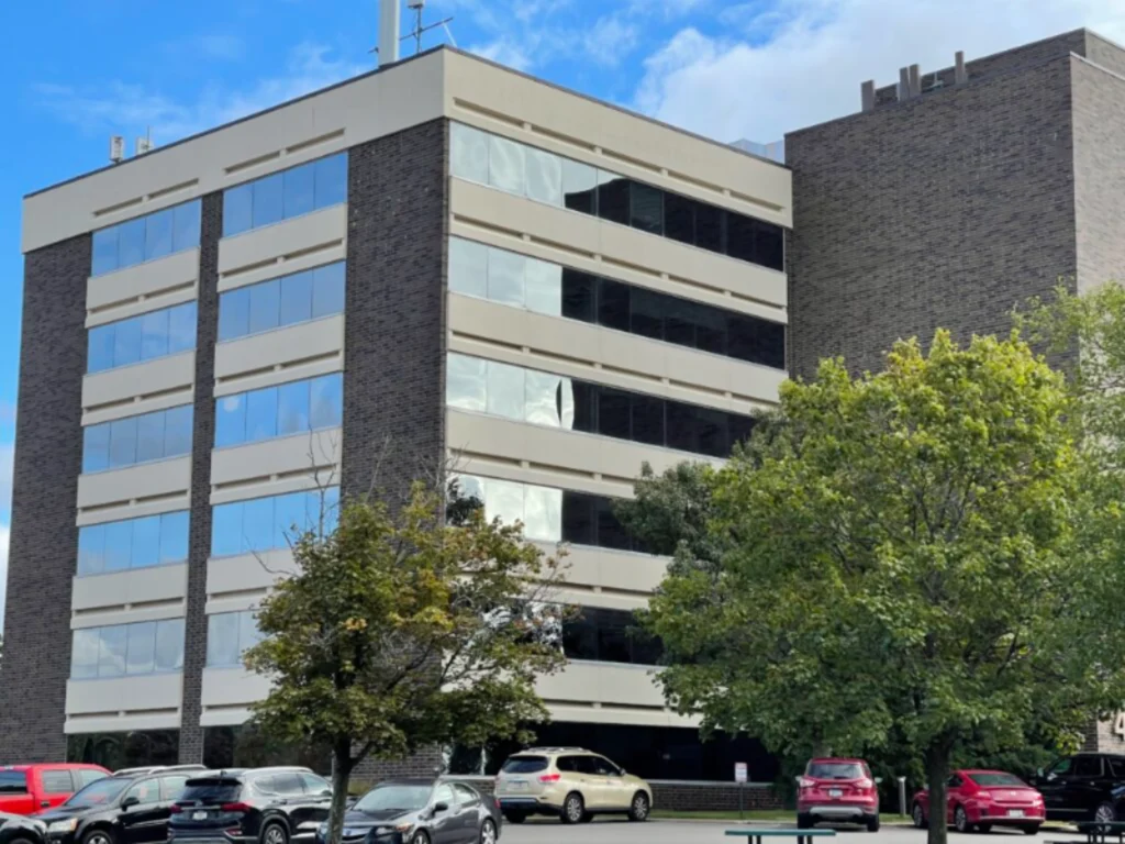 Multi-story office building with parked cars and trees