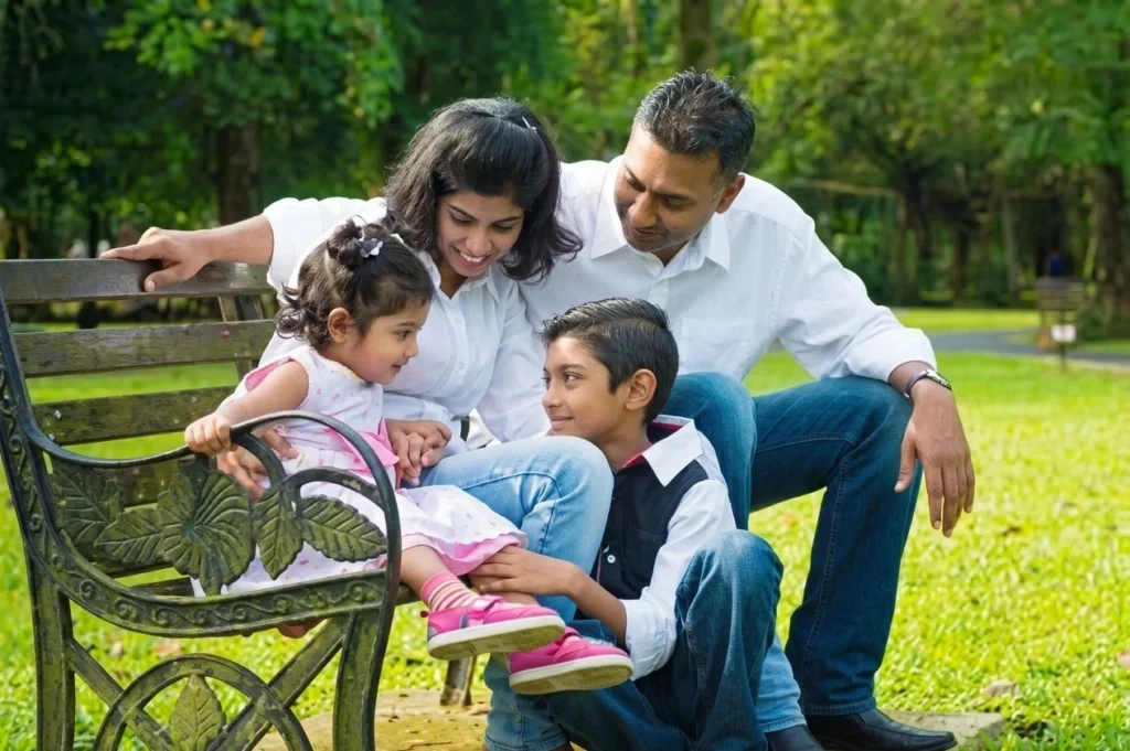Happy family sitting together on a park bench, enjoying quality time outdoors in a green garden.